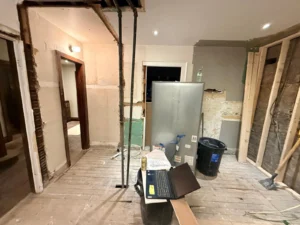 Completed legal basement suite in a Hamilton home — showing open kitchen area, egress window with window well, and adequate ceiling height meeting Ontario Building Code requirements 
