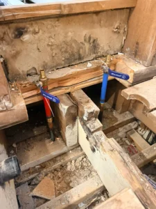 Open wall during Hamilton bathroom renovation showing old galvanized supply lines and drain rough-in — Gateway Group